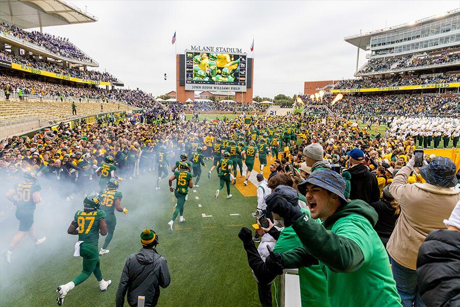 fans and players running on McLane stadium