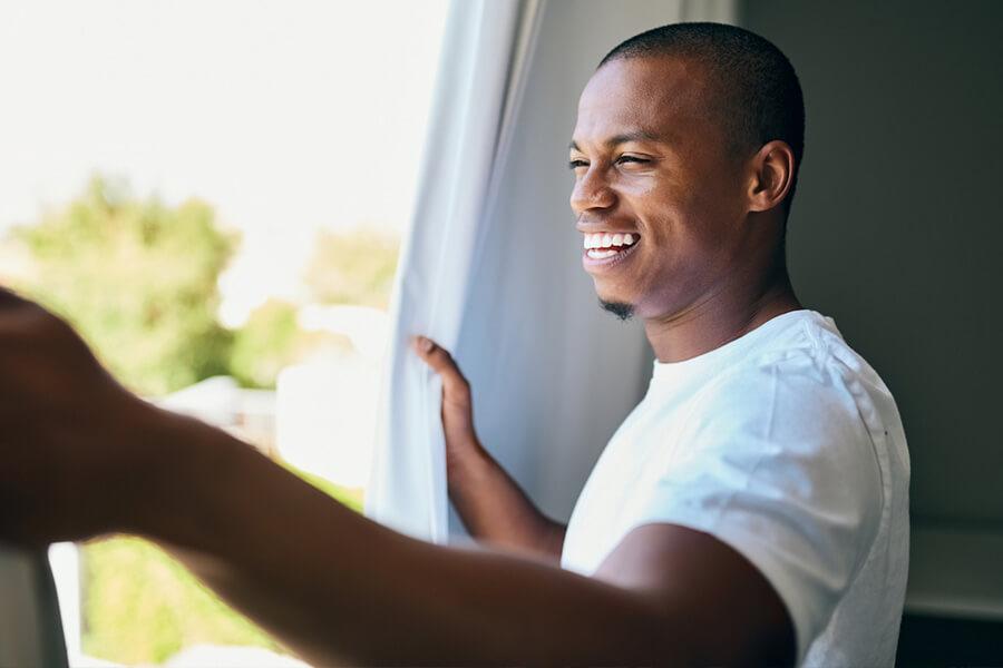 Man waking up smiling looking outside